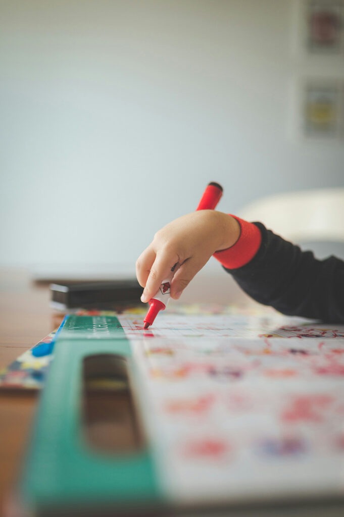 Young child learning core skills by drawing with a marker.